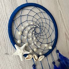 there is a blue dream catcher with shells and pearls on it, next to a starfish