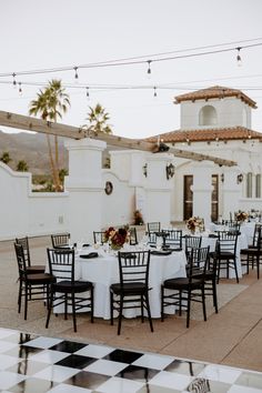 tables and chairs are set up in front of a white building with black checkered flooring