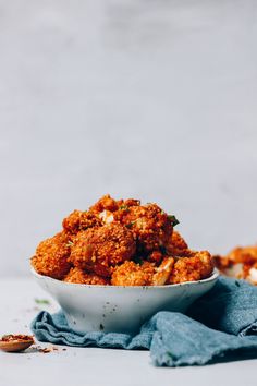 a white bowl filled with fried food on top of a blue cloth