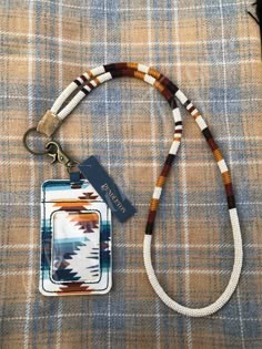 a lanyard with a tag attached to it on top of a plaid cloth surface