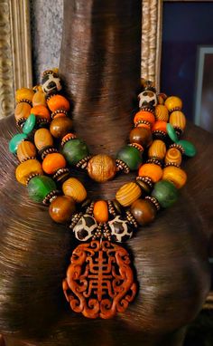 This stunning triple strand oversized beaded statement necklace will look fabulous paired with animal prints or authentic African prints. Components include zebu bone, wood, African recycled glass, quartz teardrop beads, copper daisy spacers, dark brown wood rondelles, bronze rhinestone rondelles, hand painted African glass beads, an Ethiopian copper bead and gold tone tribal spacers. A hand carved rust colored Asian pendant is the focal point which measures 2.5" x 2.5". I would describe this as a medium weight, but please remember that weight is subjective. Adjusts from 17-20" and I can add more links if requested. Silver tone hardware and a lobster claw clasp. From the Atelier of Kat Kouture. Luxury Traditional Necklace With Large Beads, Luxury Adjustable Beaded Statement Necklaces, Luxury Jeweled Statement Beaded Necklaces, Luxury Statement Beaded Necklace, Luxury Hand-strung Bohemian Beaded Necklaces, Statement Beaded Necklace With Dangling Beads, Traditional Luxury Necklace With Large Beads, Luxury Round Beads Necklaces For Festivals, Luxury Statement Beaded Necklaces With Dangling Beads