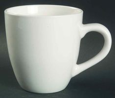 a white coffee cup sitting on top of a gray countertop next to a black wall