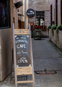 a sign that is on the sidewalk in front of a building with an open door