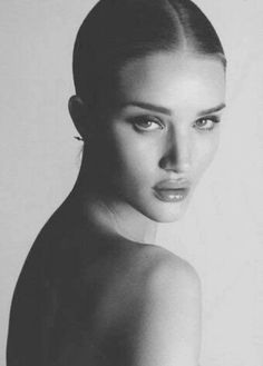 a black and white photo of a woman's face with her hair pulled back