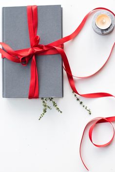 a gray box with a red ribbon tied around it and a candle on the side