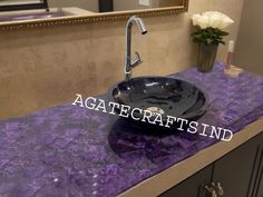 a black bowl sink sitting on top of a purple counter