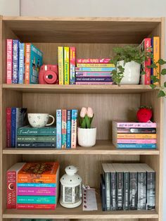 a bookshelf filled with lots of books next to a vase and potted plant