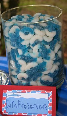 a glass filled with blue and white pretzels next to a sign that says life preservers