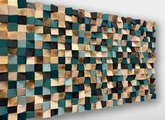 a wooden wall sculpture made out of wood blocks with green and brown squares on it