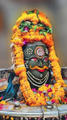 a statue with flowers around it and a man's face in the center, surrounded by other decorations