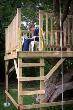 a man sitting in a chair on top of a wooden deck next to a tree