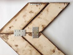 a wooden sign with metal rivets hanging from it's sides on a white wall