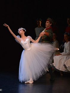 the ballerina is wearing a white tutu and has her arms outstretched