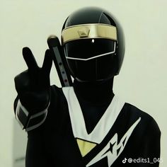 a person in a black and white uniform with a gold helmet giving the peace sign