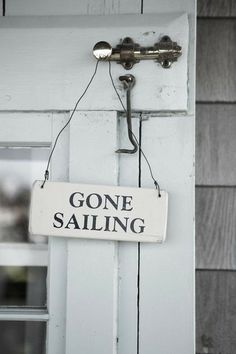 a sign that says gone sailing hanging from the side of a door with a key on it