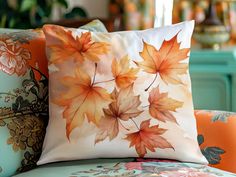 two pillows with leaves on them sitting on a couch