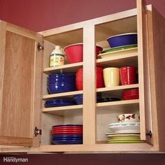 an open cabinet filled with lots of colorful bowls and plates on top of wooden shelves