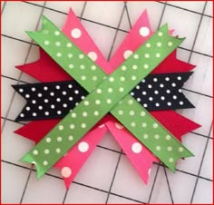 an origami bow with polka dots and ribbon on it, sitting on top of a piece of paper