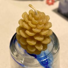 a small pine cone sitting on top of a glass jar filled with blue and white liquid