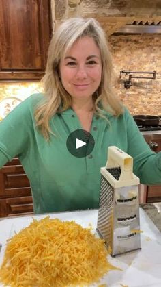 a woman sitting at a kitchen table with grated cheese on the counter next to her