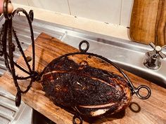 a large piece of meat is on a cutting board next to a kitchen faucet