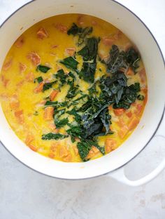 a white pot filled with soup and vegetables