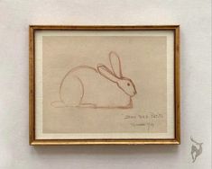 a drawing of a rabbit is hanging on the wall next to a framed painting with writing underneath it