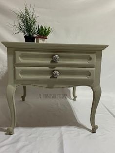 a small table with two drawers and a potted plant on top