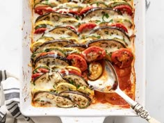 a casserole dish filled with zucchini, tomatoes and other veggies