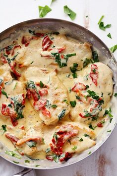 a pan filled with ravioli covered in cheese and spinach leaves next to a fork