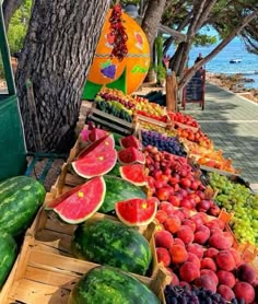 watermelons, melons and other fruits are on display at a market near the ocean