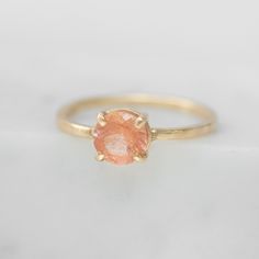 Get the *wow* factor with this one of a kind peach sunstone solitaire. Featuring an ethically sourced Oregon sunstone, the Maxine Ring is handcrafted from recycled 14k gold and a single prong setting. Ready to ship in a size 6. What makes this stone special? Sunstones are best known for their tiny, metallic-like inclusions. When light hits these golden inclusions they illuminate the sunstone giving it a gorgeous, glimmering effect. This shimmering optical illusion is called "aventurescence" and Paper Ring Box, Signature Ring, Oregon Sunstone, Signature Rings, Paper Ring, Wow Factor, Peach Rings, Body Chain Jewelry, Optical Illusion