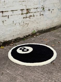 a black and white rug on the ground next to a brick wall with a number eight