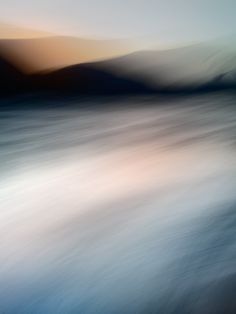 blurry photograph of water with mountains in the background