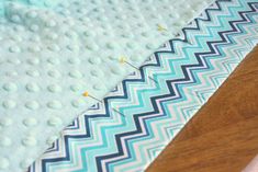 a close up of a quilt on a wooden floor with blue and white chevrons