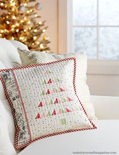 a white couch with pillows and a christmas tree