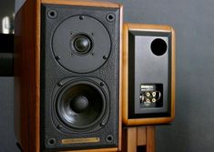 two speakers are sitting next to each other on a stand in front of a gray wall