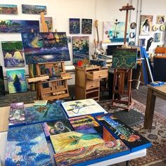 an artist's studio with many paintings and easels on the floor in front of them