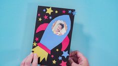 a hand holding up a card with a rocket ship on it