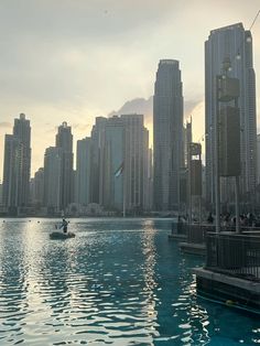 a man in a boat on the water near some tall buildings