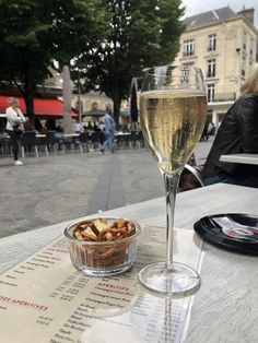 a glass of wine sitting on top of a table next to a bowl of food