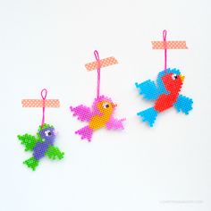 three cross stitch bird ornament hanging on a white background with polka dot ribbon