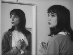 a woman standing in front of a mirror looking at her reflection