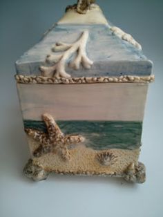 a ceramic box with sand and shells on it