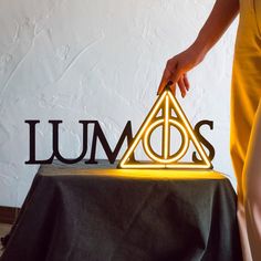 a person standing next to a table with a light up harry potter logo on it