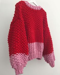 a red and pink sweater hanging on a white wall