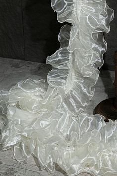 a white wedding dress with ruffles on the bottom and skirt is laying on the floor