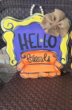 a wooden sign that says hello friend and sits on a wicker chair with a bow