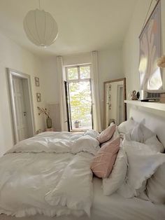 a bed with white sheets and pillows in a bedroom