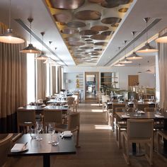 an empty restaurant with tables and chairs in the center, along with hanging lights on the ceiling